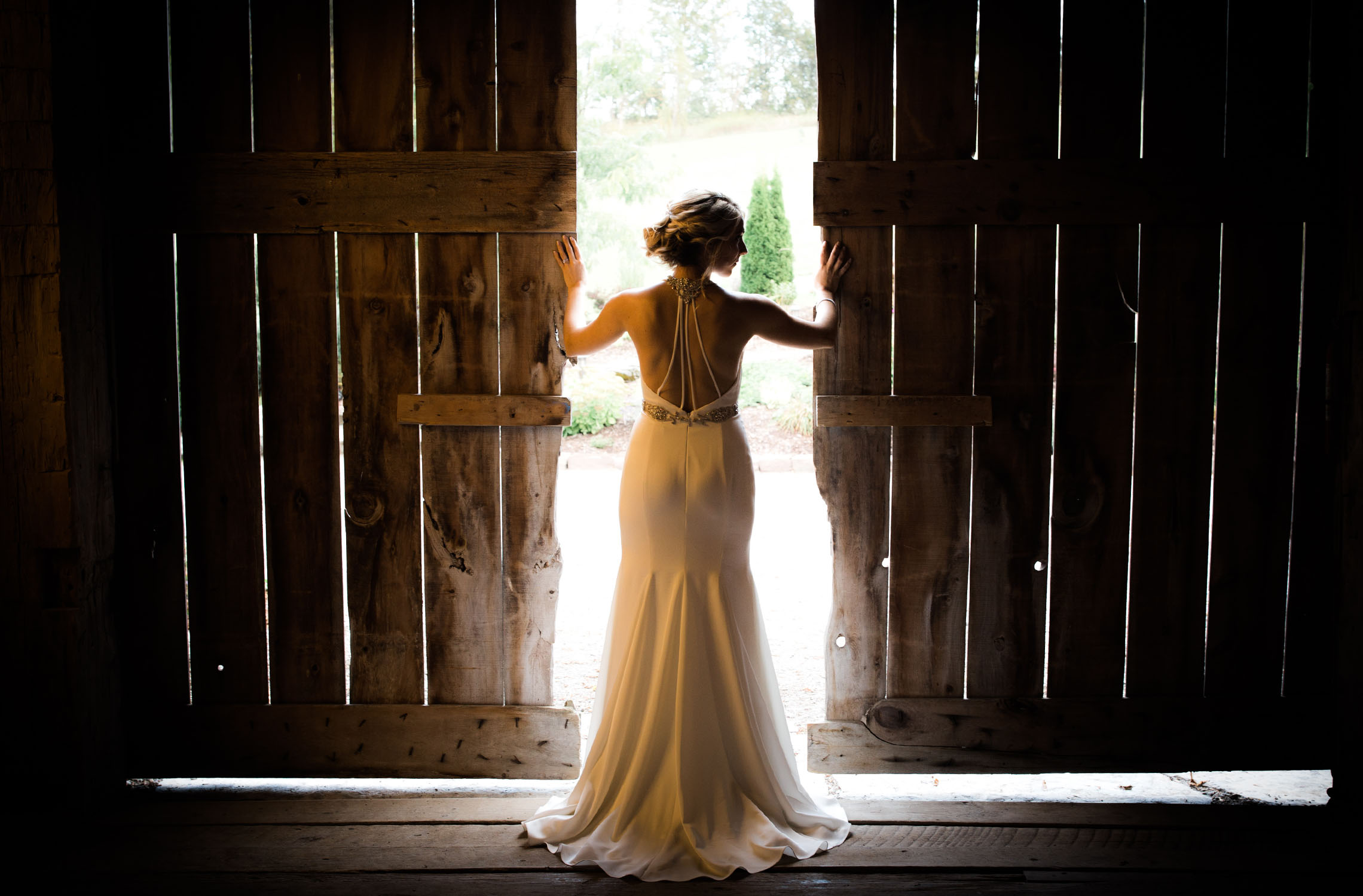 Gorgeous shot of bride with sunlight streaming thru the gaps of the old barn.