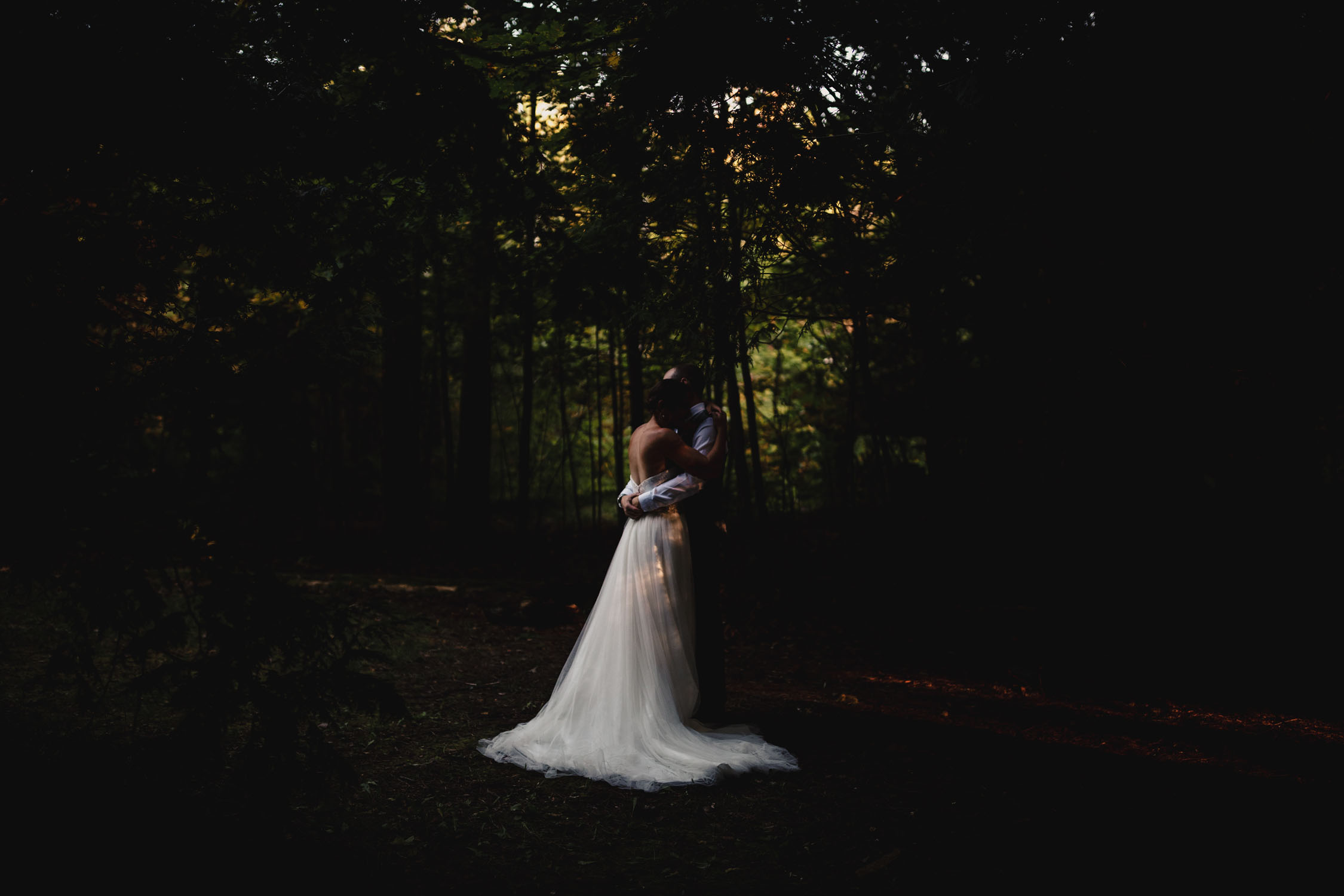 Gorgeous couple kissing off to the side in the middle of the forest.