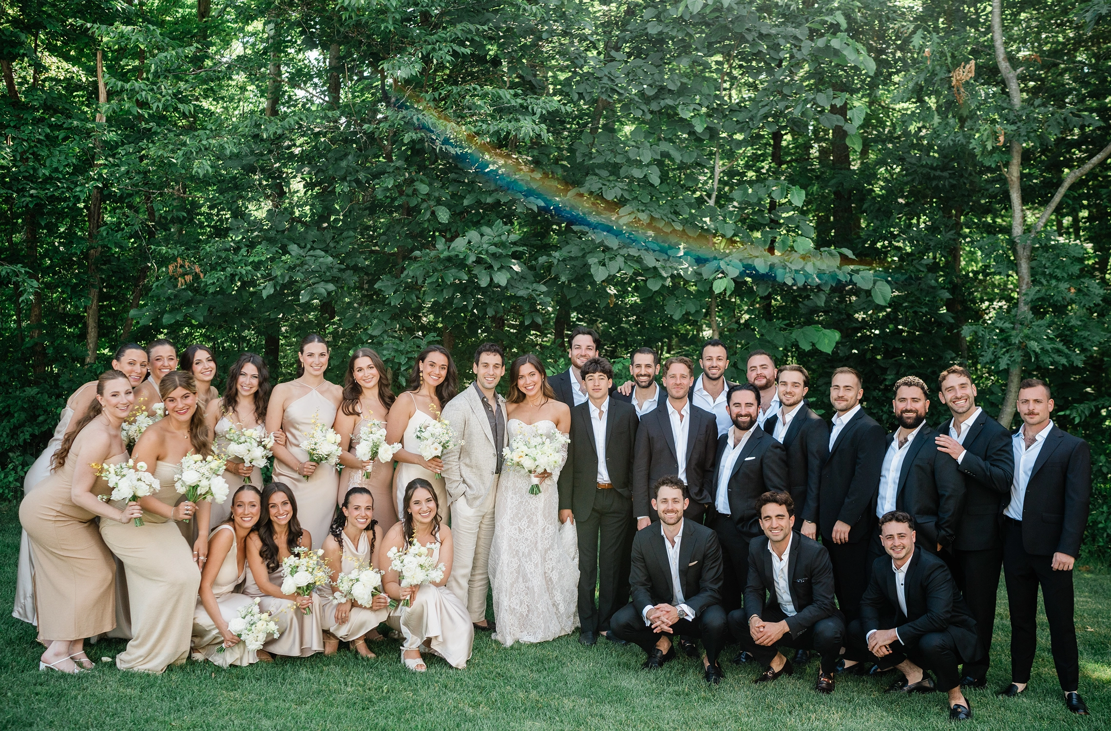 Large wedding party portrait in the gardens at Compass Rose Suites.