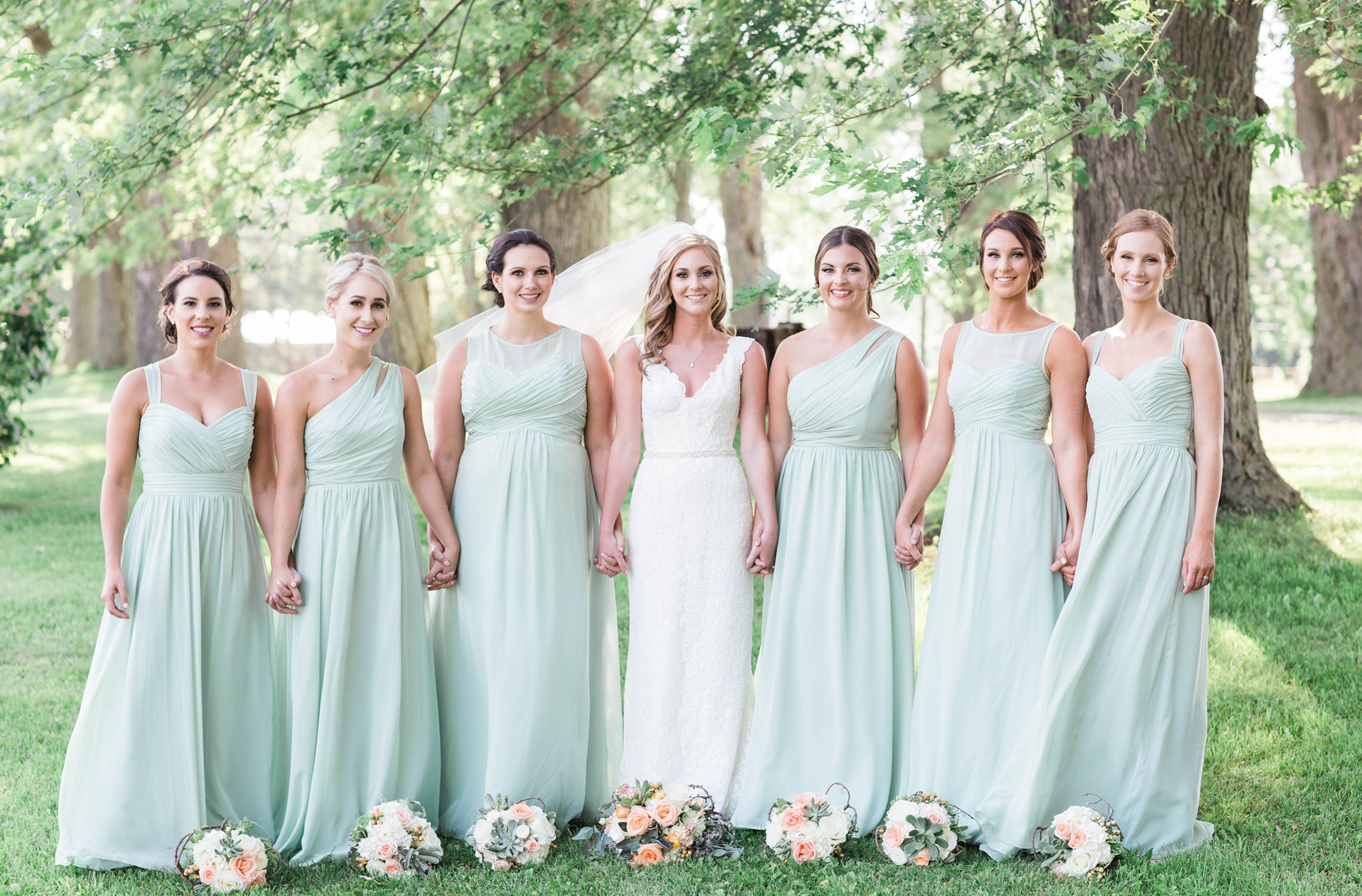 Bride and maids posing for formal picture. all wearing sea foam green dresses.