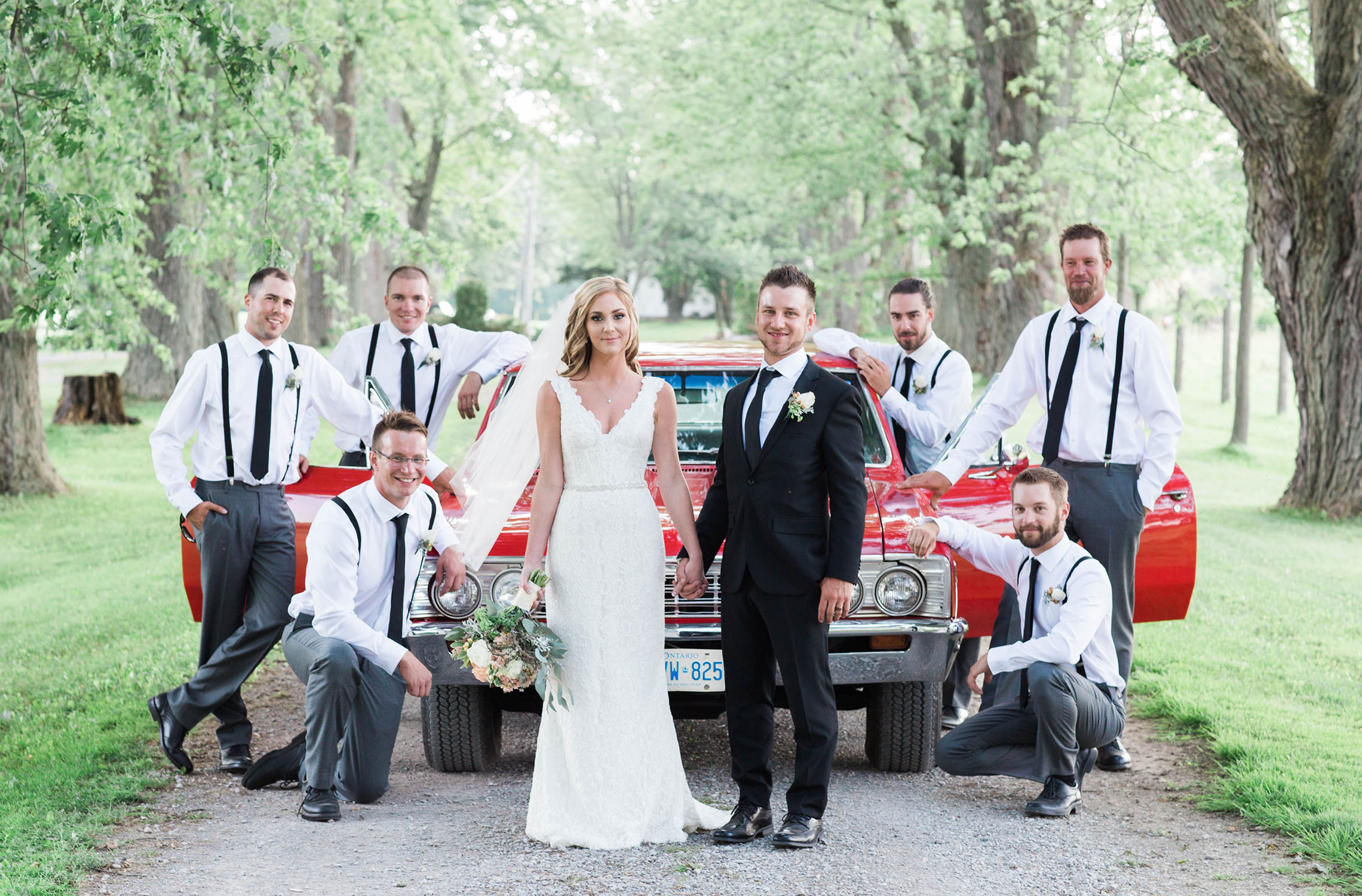 Couple with grooms men in front of classic car.