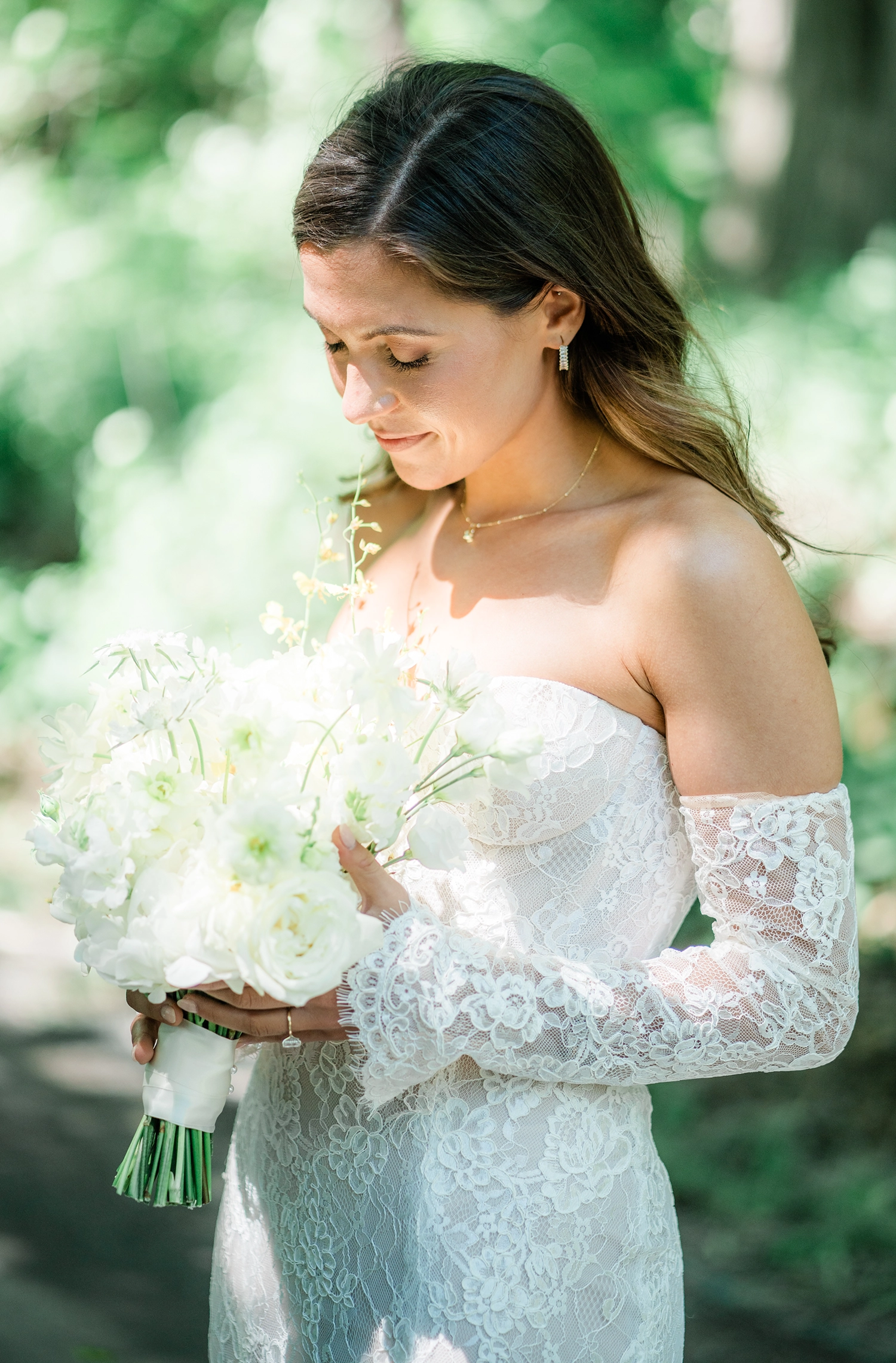 Bride holding white bouquet in dappled shade at Compass Rose Suites.