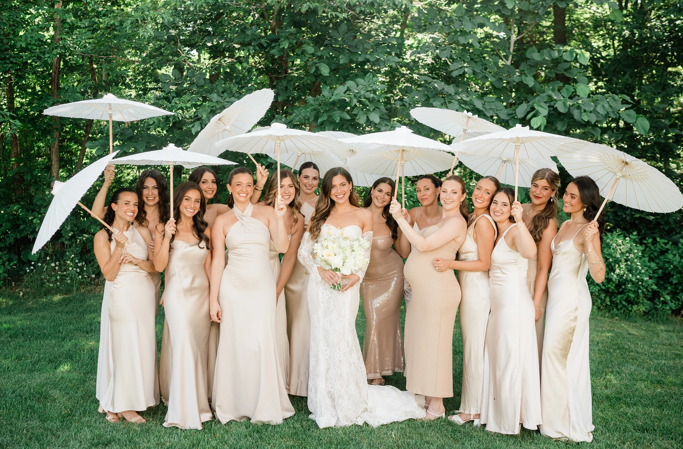 Bridesmaids with white parasols on the lawn at Compass Rose Suites.
