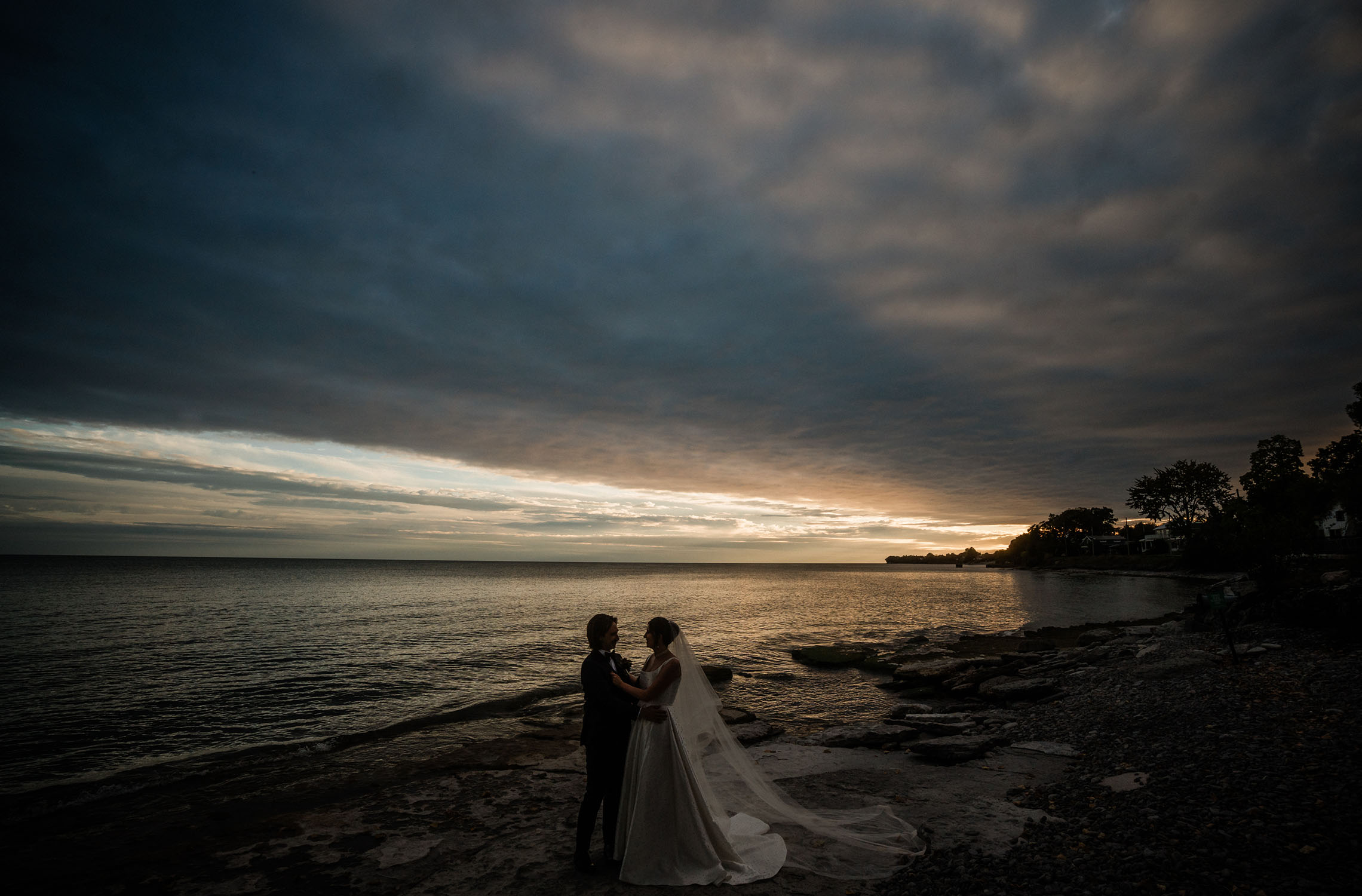 Bride and groom walking by Lake Ontario at Drake Devonshire sunset wedding